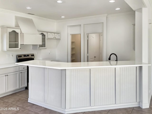 kitchen with premium range hood, a center island with sink, white cabinets, light tile patterned floors, and ornamental molding