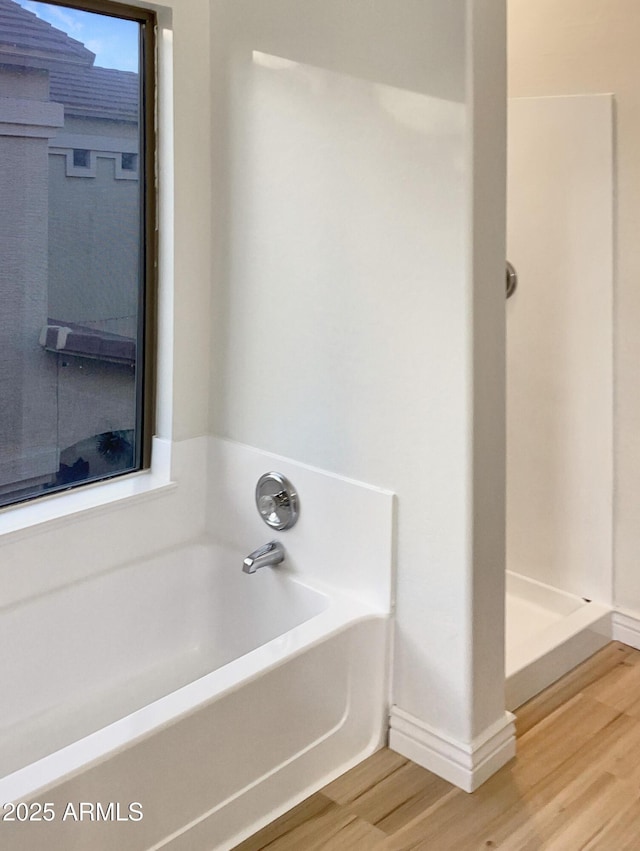 bathroom with wood-type flooring and a tub