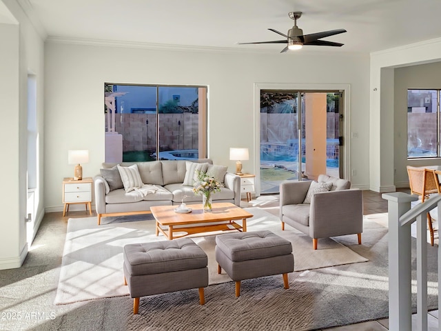 living room with ceiling fan, crown molding, and light colored carpet