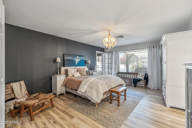 bedroom with a chandelier, light wood finished floors, and visible vents