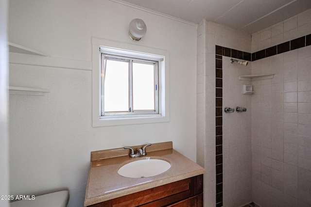 bathroom with toilet, a tile shower, sink, and crown molding