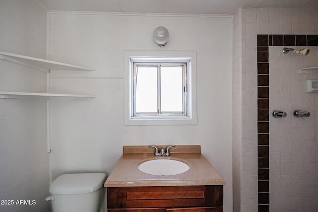 bathroom with tiled shower, vanity, and toilet