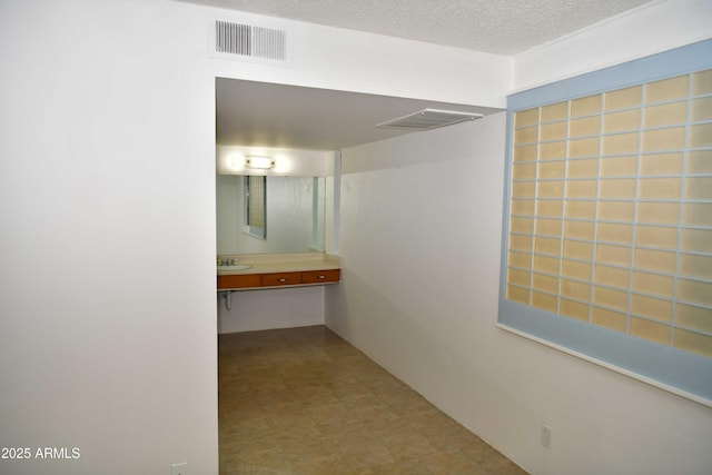 corridor featuring a textured ceiling and sink