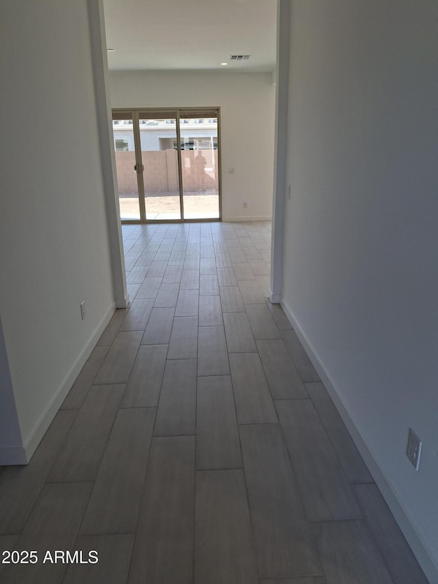 hall with baseboards and visible vents