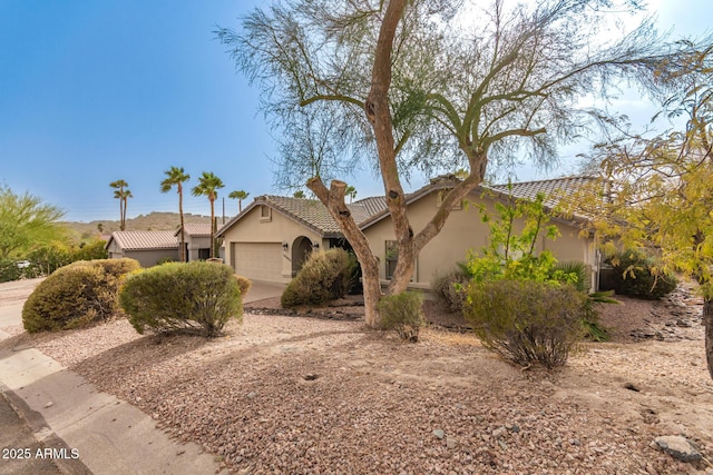 view of front of house featuring a tiled roof, an attached garage, and stucco siding