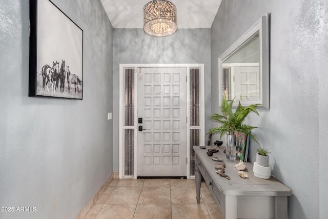 entryway with light tile patterned floors, baseboards, and an inviting chandelier