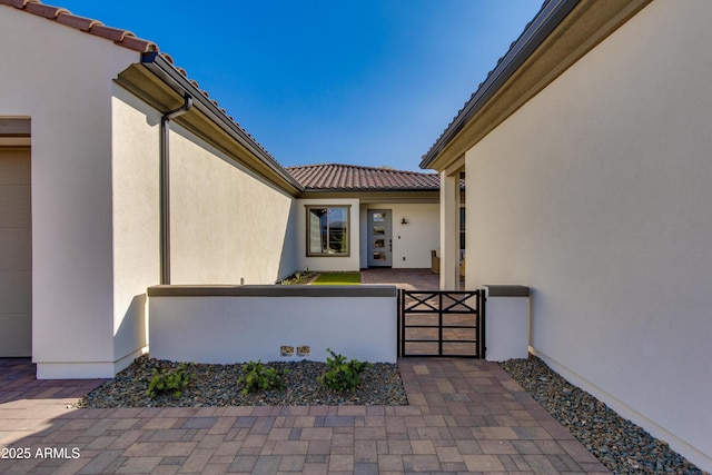 3281 Maverick Dr, Wickenburg, AZ 85390 - view of exterior entry featuring stucco siding, a gate, fence, and a tile roof