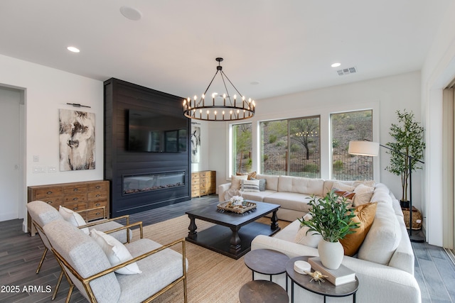 3281 Maverick Dr, Wickenburg, AZ 85390 - living room with a large fireplace, visible vents, an inviting chandelier, and wood finished floors