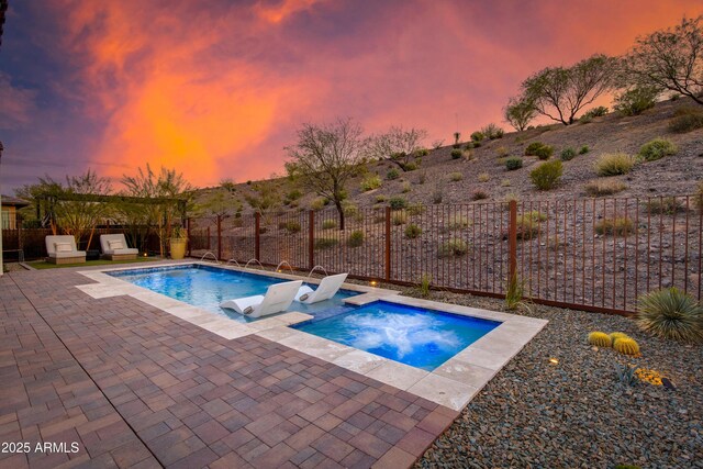3281 Maverick Dr, Wickenburg, AZ 85390 - pool at dusk with an in ground hot tub, fence, and a patio area