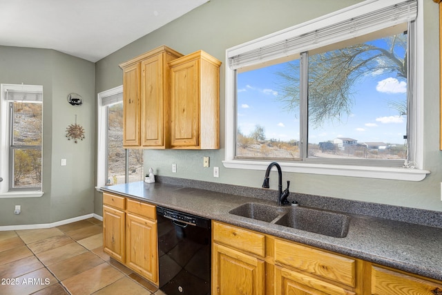 kitchen featuring light tile patterned floors, dark countertops, a sink, dishwasher, and baseboards