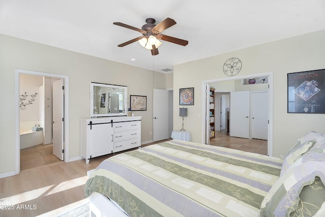 bedroom with visible vents, baseboards, ceiling fan, ensuite bathroom, and light wood-style floors