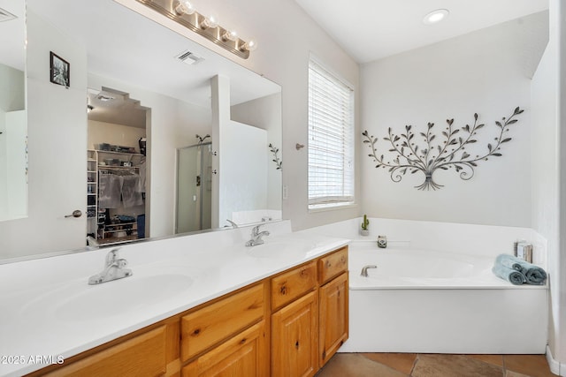 full bath featuring a stall shower, a sink, visible vents, and a walk in closet