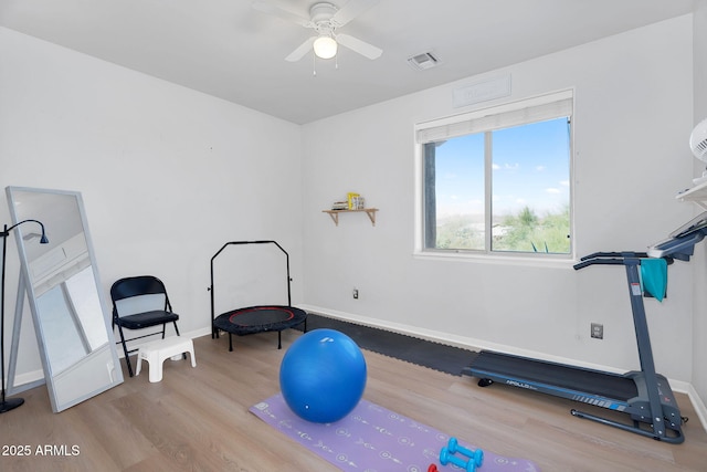 workout area featuring ceiling fan, wood finished floors, visible vents, and baseboards