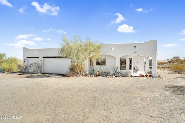 southwest-style home featuring a garage, driveway, and stucco siding