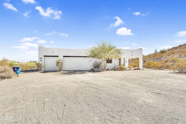 pueblo-style home with a garage, driveway, and stucco siding