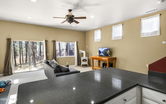 4371 E Savannah Cir, Flagstaff, AZ 86004 - interior space with visible vents, a wood stove, a ceiling fan, and light colored carpet