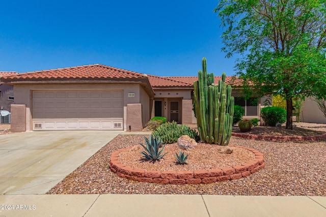 view of front facade with a garage, driveway, a tile roof, and stucco siding