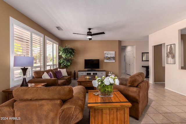 living area with light tile patterned flooring, ceiling fan, visible vents, and baseboards