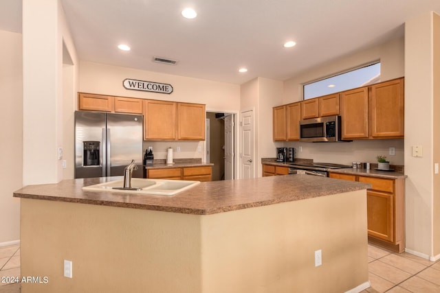 kitchen with light tile patterned floors, visible vents, a kitchen island with sink, stainless steel appliances, and a sink