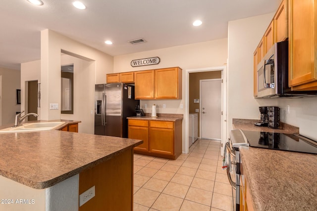 kitchen featuring visible vents, appliances with stainless steel finishes, washing machine and clothes dryer, a sink, and recessed lighting