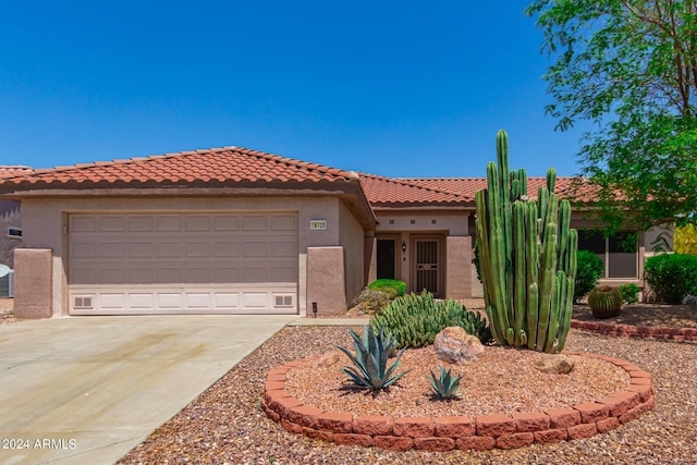 mediterranean / spanish home with an attached garage, a tile roof, concrete driveway, and stucco siding