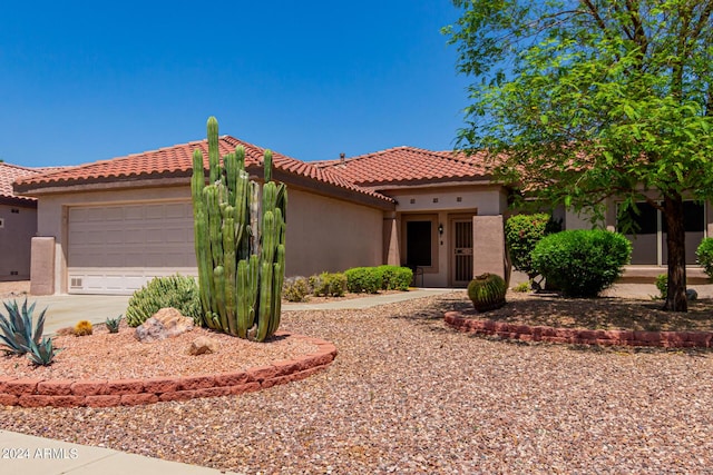 mediterranean / spanish house featuring a tiled roof, concrete driveway, an attached garage, and stucco siding