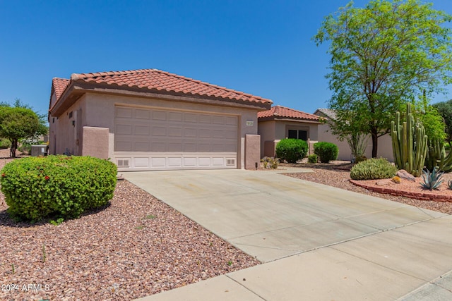 mediterranean / spanish-style home featuring concrete driveway, an attached garage, a tiled roof, and stucco siding