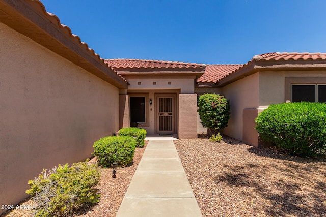 property entrance featuring a tile roof and stucco siding