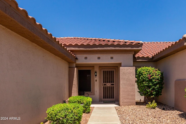 property entrance featuring a tiled roof and stucco siding