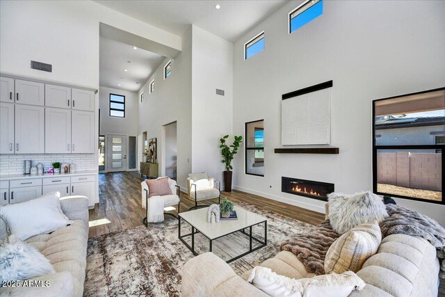 3335 W Desert Dawn Dr, Phoenix, AZ 85083 - living area with a towering ceiling, wood finished floors, a glass covered fireplace, baseboards, and recessed lighting