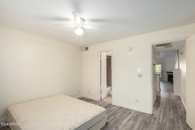 bedroom featuring ceiling fan, connected bathroom, light hardwood / wood-style flooring, and a walk in closet