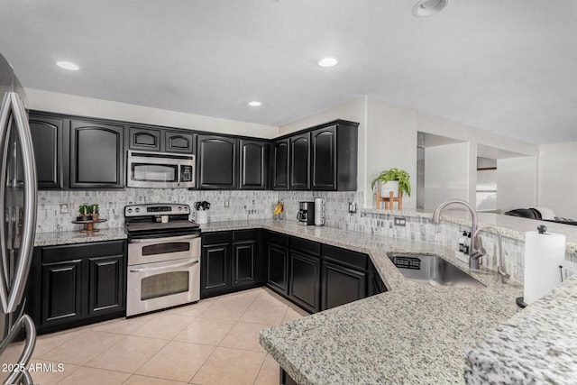 kitchen with stainless steel appliances, backsplash, a sink, and dark cabinets