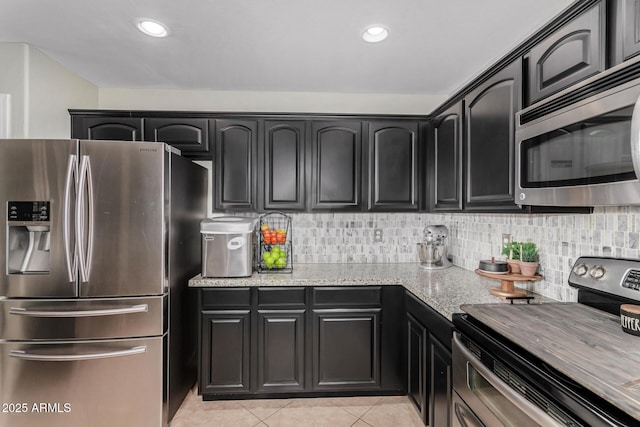 kitchen with light tile patterned floors, decorative backsplash, appliances with stainless steel finishes, light stone countertops, and recessed lighting