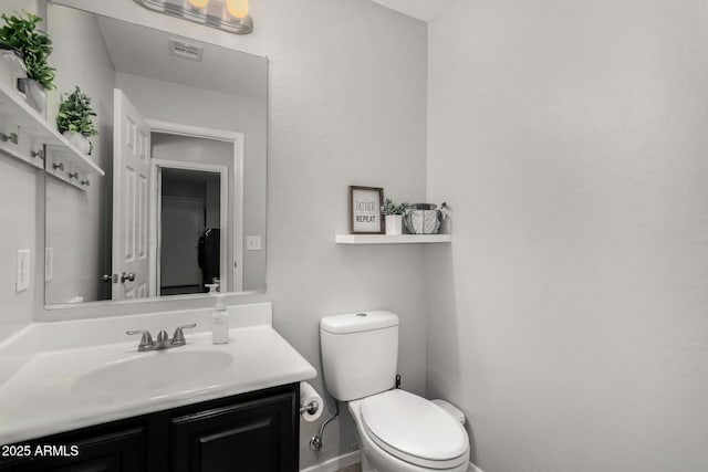 bathroom featuring toilet, vanity, and baseboards