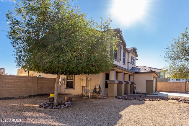 exterior space with a tile roof, fence, and stucco siding