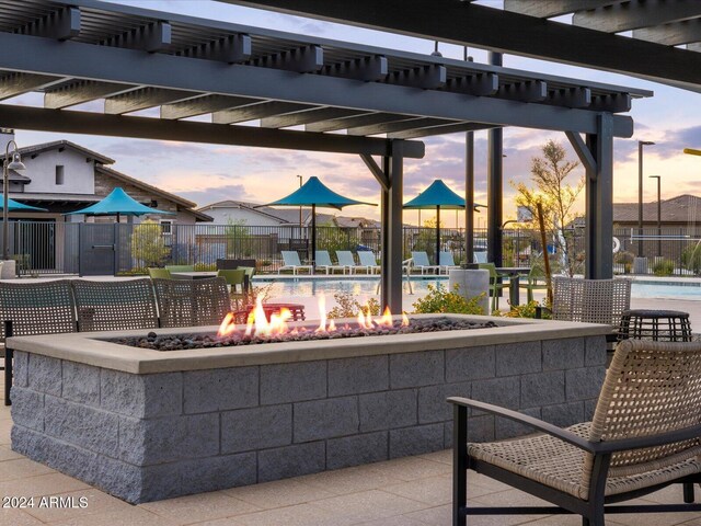 patio terrace at dusk with a pergola and an outdoor fire pit