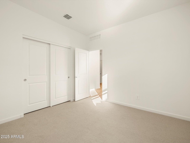 unfurnished bedroom featuring light carpet and a closet