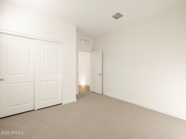 unfurnished bedroom featuring light carpet and a closet