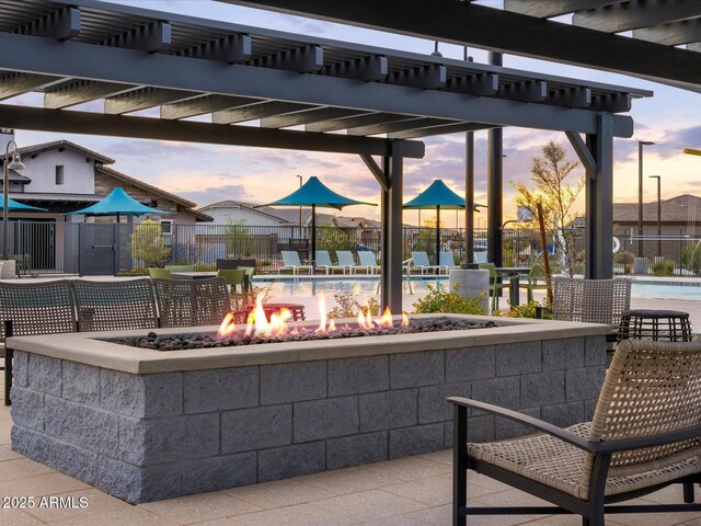 patio terrace at dusk featuring a pergola and a fire pit