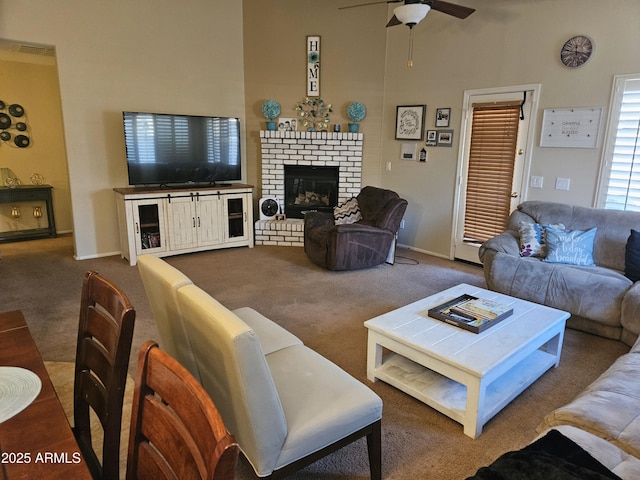 carpeted living room featuring ceiling fan, a towering ceiling, and a fireplace