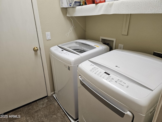 clothes washing area with dark tile patterned flooring and washer and dryer