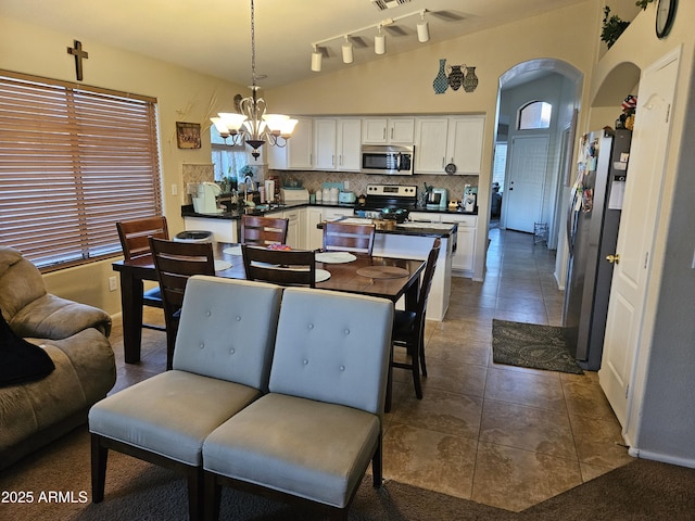 dining area with sink, a chandelier, vaulted ceiling, and dark tile patterned flooring