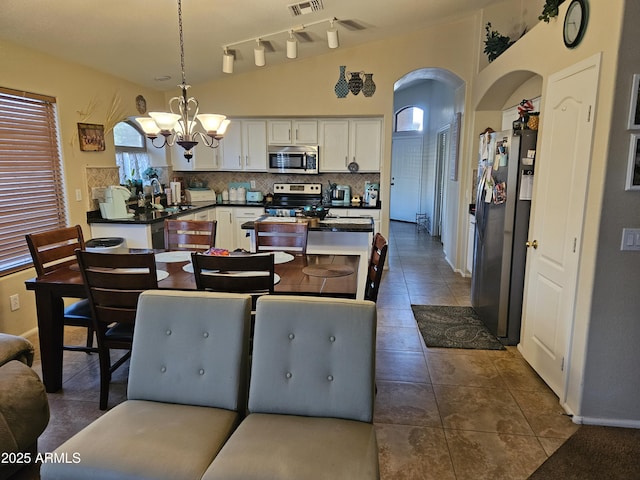 dining room with an inviting chandelier, lofted ceiling, sink, and dark tile patterned floors