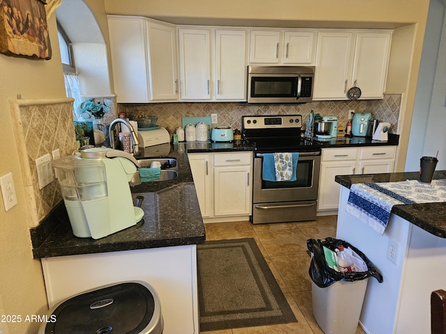 kitchen with sink, white cabinetry, tasteful backsplash, light tile patterned floors, and stainless steel appliances