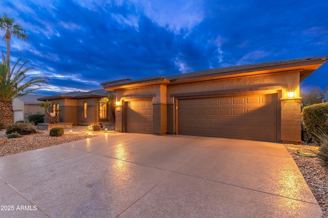 prairie-style home with driveway, a garage, and stucco siding