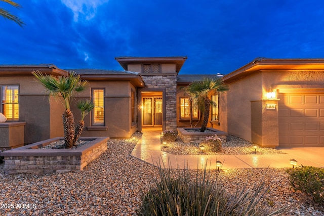 view of front facade featuring stone siding, an attached garage, and stucco siding