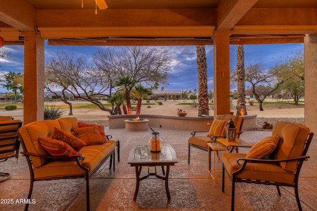 view of patio featuring ceiling fan and an outdoor living space with a fire pit