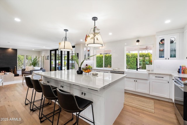 kitchen featuring white cabinetry, sink, light stone counters, a kitchen bar, and a kitchen island