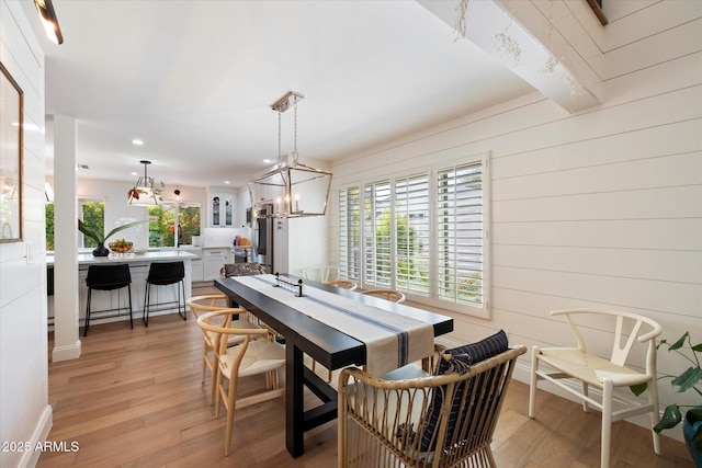 dining room with wood walls, light wood-type flooring, and a chandelier