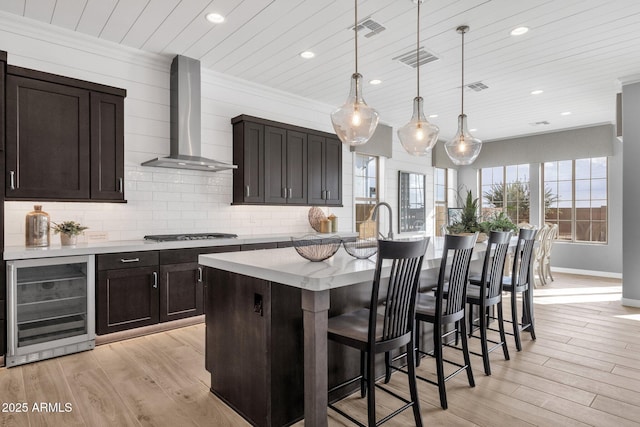 1145 E Gleneagle Dr, Chandler, AZ 85249 - kitchen with beverage cooler, wall chimney exhaust hood, recessed lighting, light countertops, and light wood-type flooring